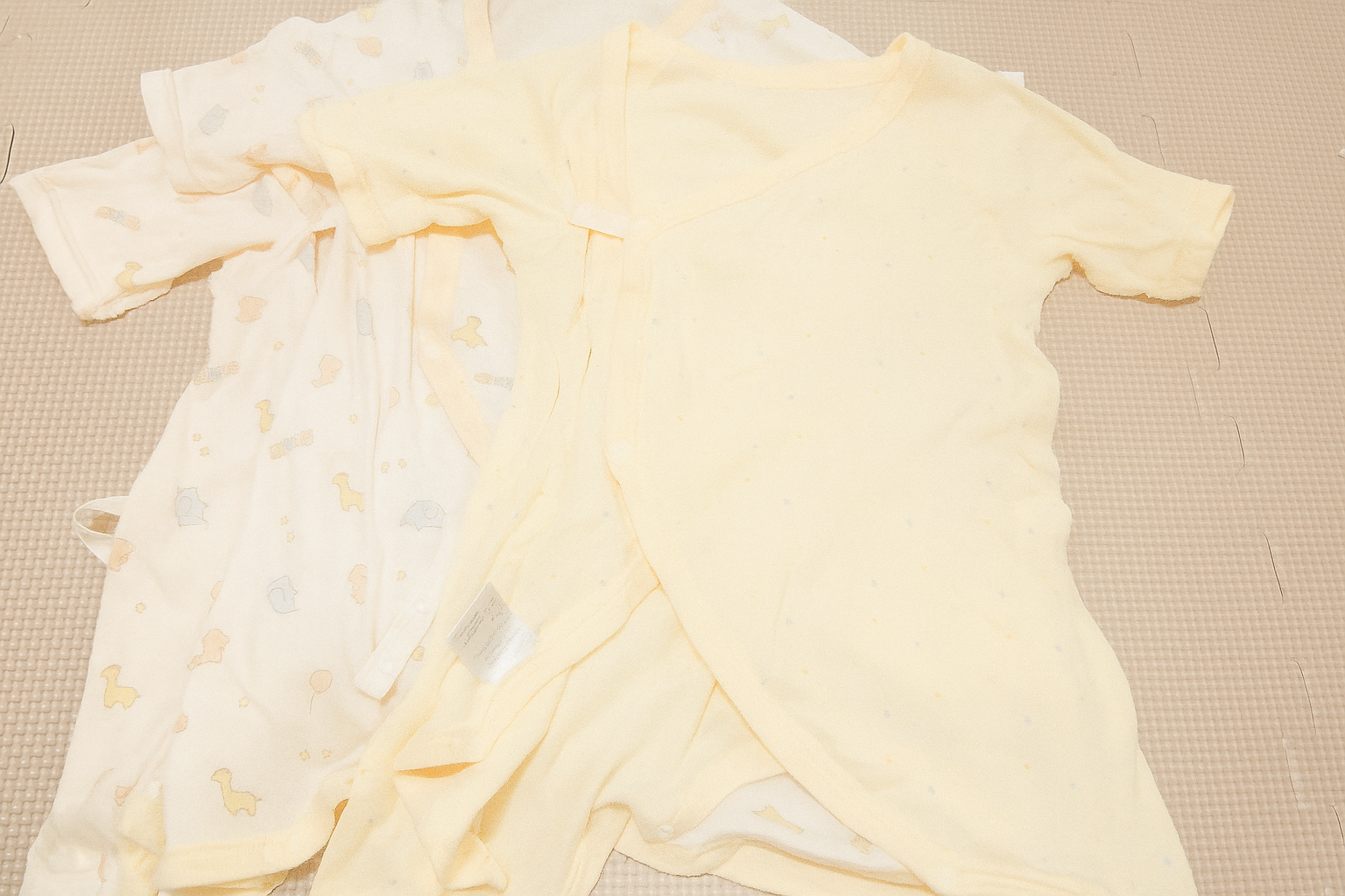 冬生まれの赤ちゃん用のコンビ肌着が2着並んだ写真。やさしい黄色を基調としたコットン素材のベビー肌着で、出産準備や新生児の服装選びの参考になる。